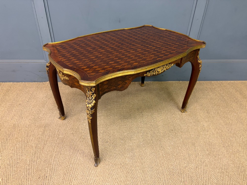 A French Louis XV style low coffee table featuring a serpentine parquetry top, curved cabriole legs, and ornate gilt-bronze mounts.