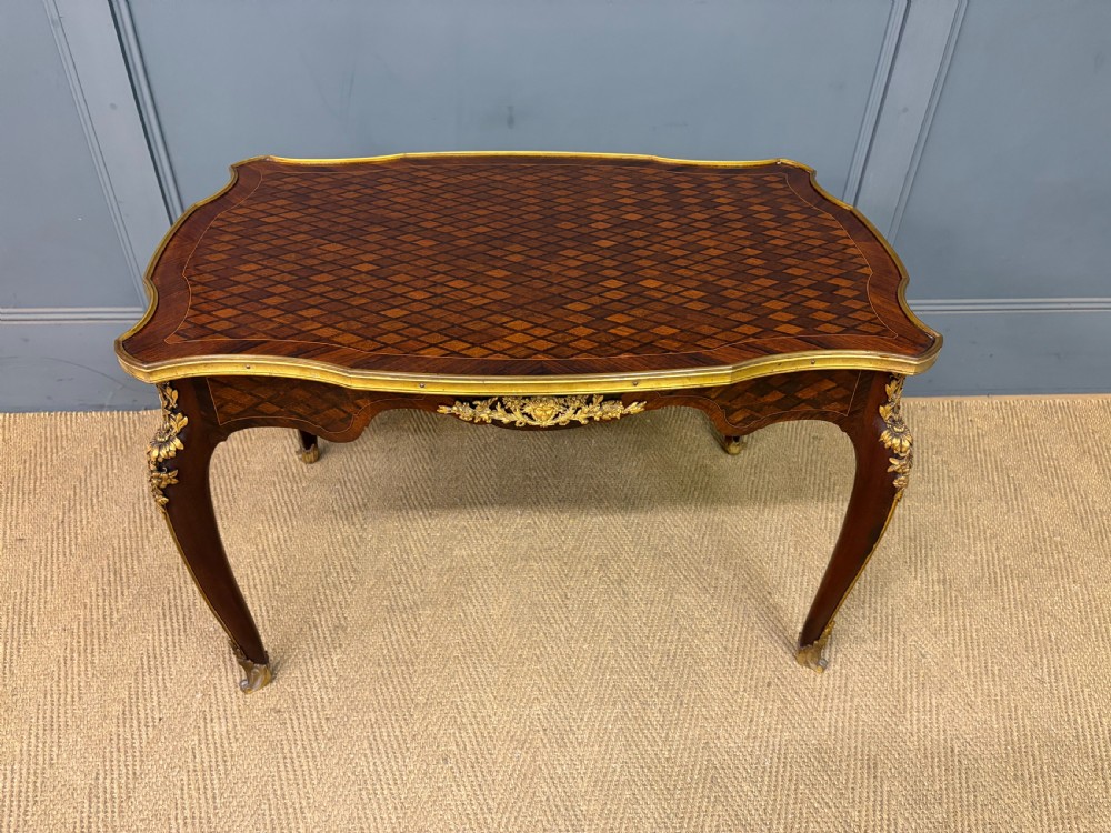 A French Louis XV style low coffee table featuring a serpentine parquetry top, curved cabriole legs, and ornate gilt-bronze mounts. View III