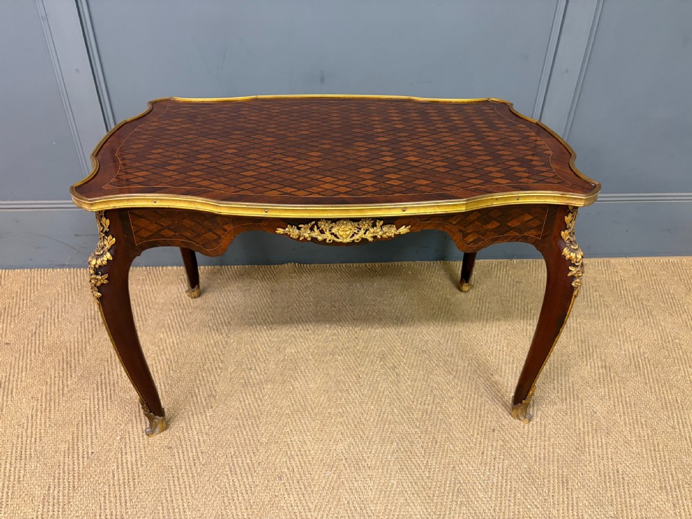 A French Louis XV style low coffee table featuring a serpentine parquetry top, curved cabriole legs, and ornate gilt-bronze mounts. View IV