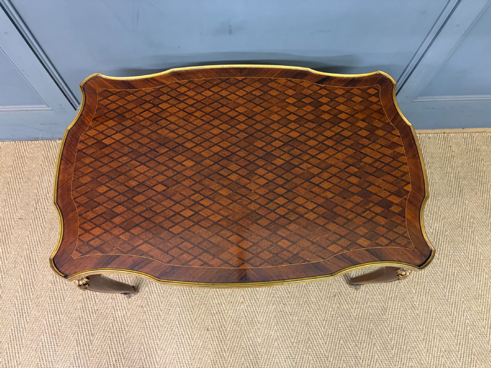 A French Louis XV style low coffee table featuring a serpentine parquetry top, curved cabriole legs, and ornate gilt-bronze mounts. View VI