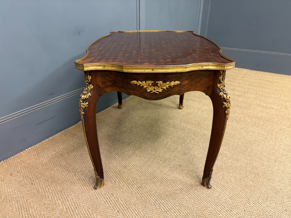 A French Louis XV style low coffee table featuring a serpentine parquetry top, curved cabriole legs, and ornate gilt-bronze mounts. View VIII