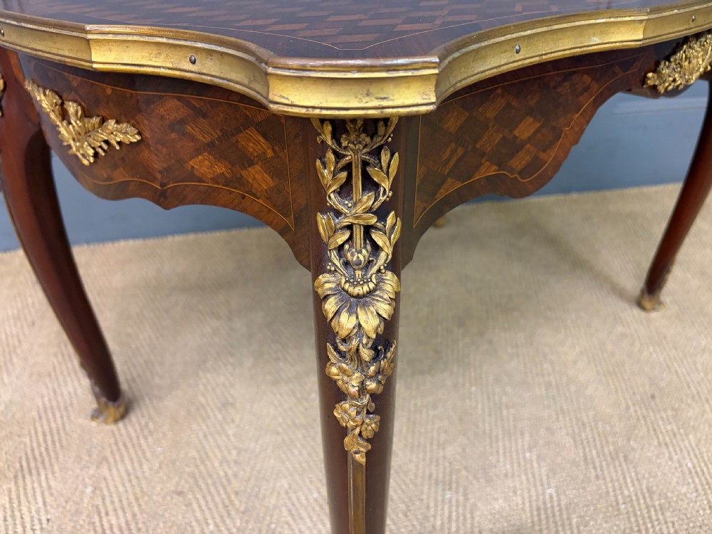 A French Louis XV style low coffee table featuring a serpentine parquetry top, curved cabriole legs, and ornate gilt-bronze mounts. View X