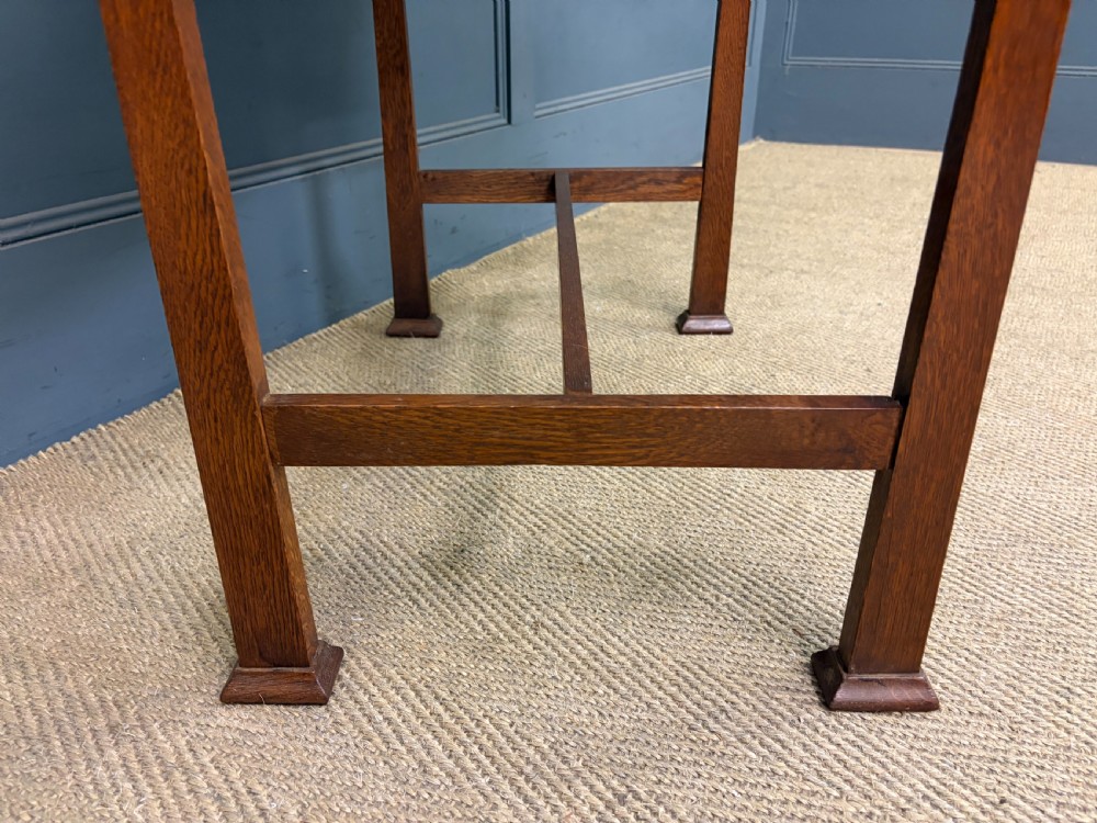 An Arts and Crafts period oak writing desk featuring an inset green leather top, single frieze drawer with brass handles, and pierced side supports. View XII