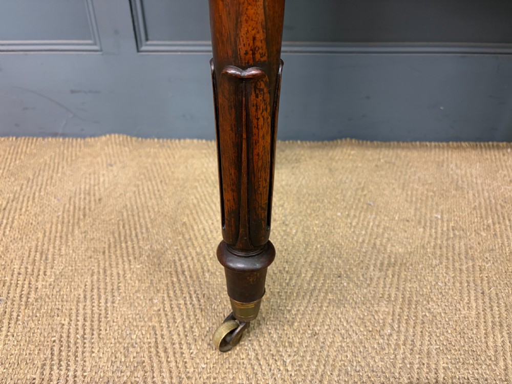 An early Victorian rosewood card table featuring a figured fold-over top, rectangular apron, turned tapered legs, and original brass castors. View III