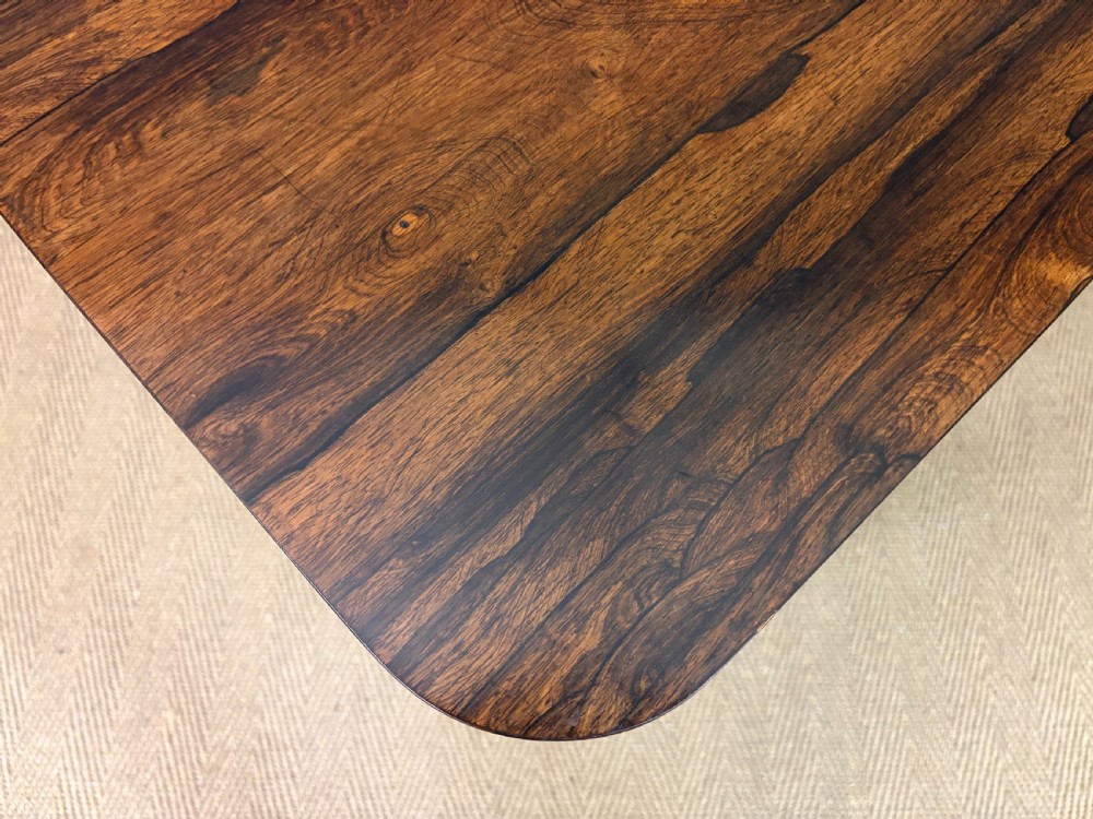 An early Victorian rosewood card table featuring a figured fold-over top, rectangular apron, turned tapered legs, and original brass castors. View XI