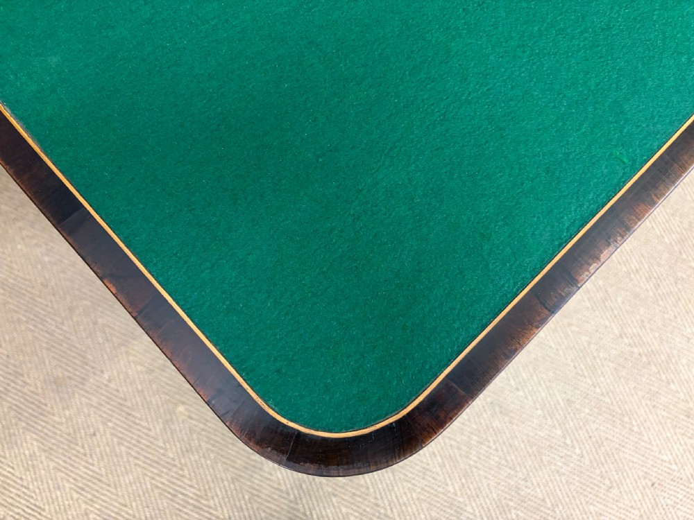 An early Victorian rosewood card table featuring a figured fold-over top, rectangular apron, turned tapered legs, and original brass castors. View XVII