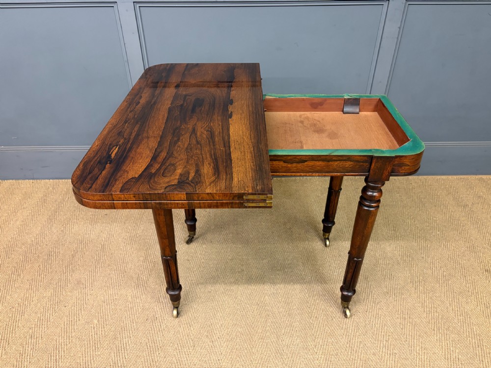 An early Victorian rosewood card table featuring a figured fold-over top, rectangular apron, turned tapered legs, and original brass castors. View XVIII