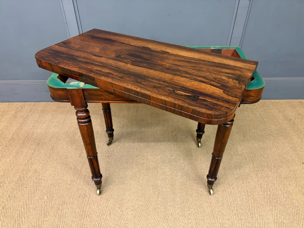 An early Victorian rosewood card table featuring a figured fold-over top, rectangular apron, turned tapered legs, and original brass castors. View XIX
