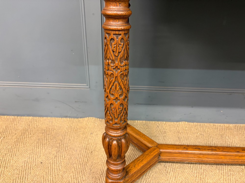A tall carved oak display cabinet featuring three glass shelves, glazed sides, a carved frieze drawer, and carved turned legs. View XIII