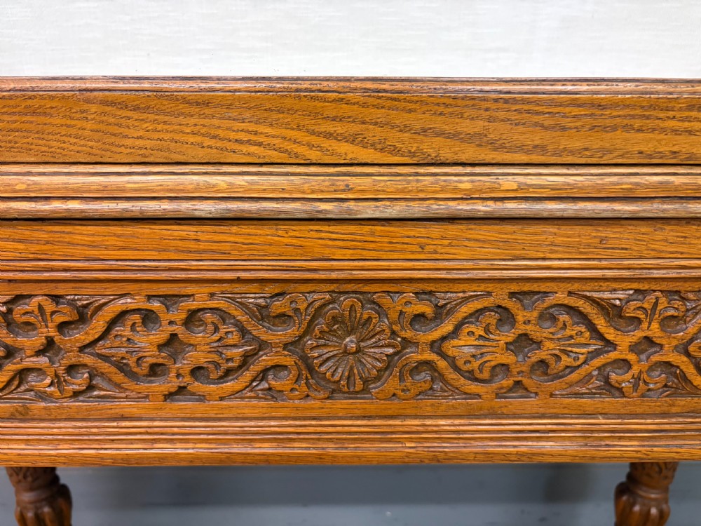 A tall carved oak display cabinet featuring three glass shelves, glazed sides, a carved frieze drawer, and carved turned legs. View XIV