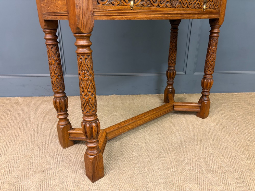 A tall carved oak display cabinet featuring three glass shelves, glazed sides, a carved frieze drawer, and carved turned legs. View XIX