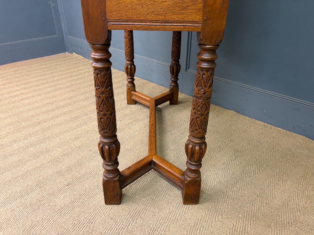A tall carved oak display cabinet featuring three glass shelves, glazed sides, a carved frieze drawer, and carved turned legs. View XXI