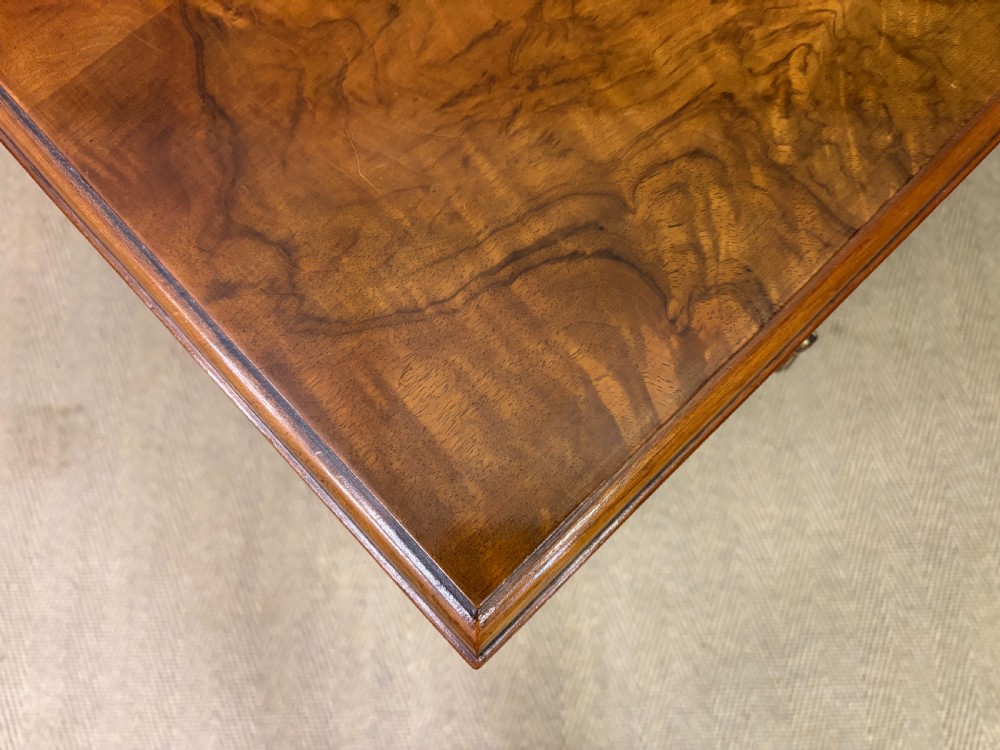 An Art Deco burr walnut chest of four full-width drawers featuring figured veneer panels, decorative brass drop handles, and low bracket feet. View XI