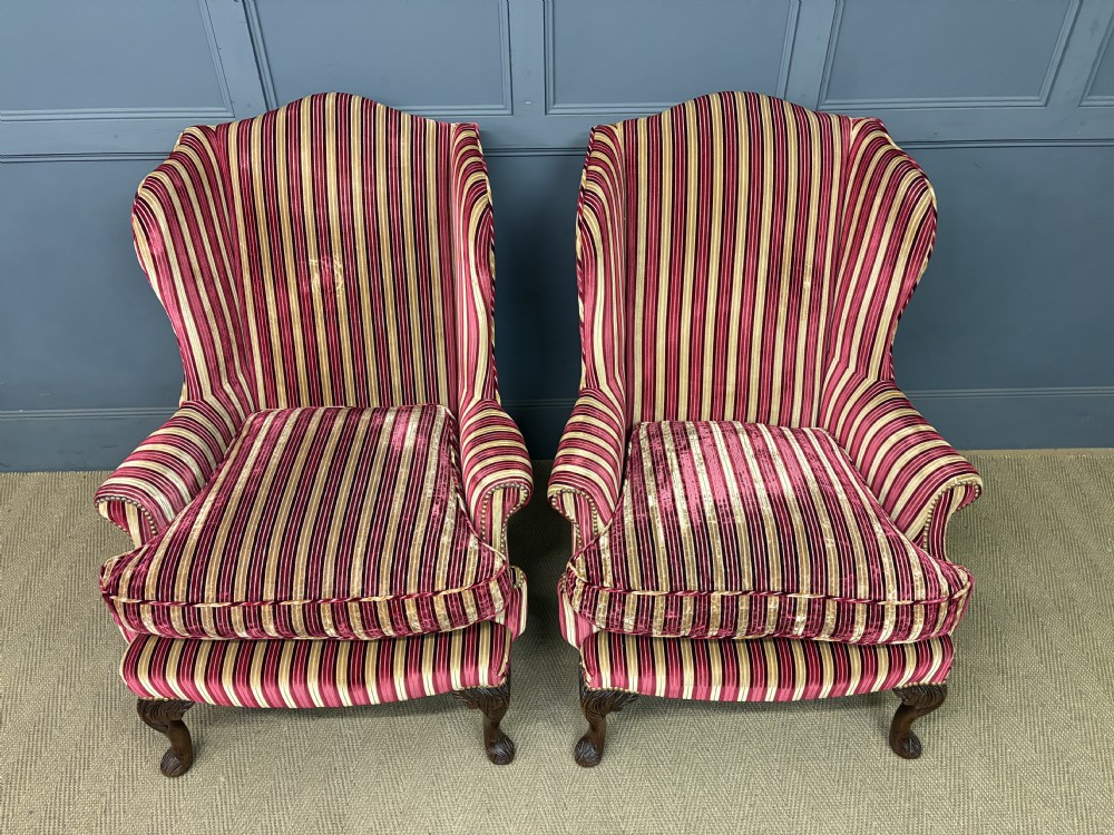 A pair of high-backed wing armchairs upholstered in red and gold striped velvet fabric with carved timber cabriole legs. View V