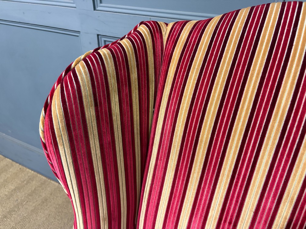 A pair of high-backed wing armchairs upholstered in red and gold striped velvet fabric with carved timber cabriole legs. View XII