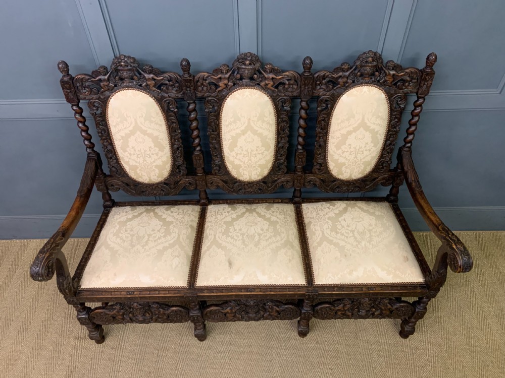 A 19th-century Carolean style carved walnut settee with three oval back panels upholstered in cream damask fabric, featuring barley twist uprights and intricate scrollwork. View III