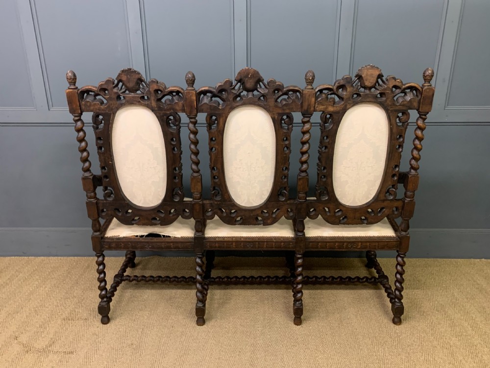 A 19th-century Carolean style carved walnut settee with three oval back panels upholstered in cream damask fabric, featuring barley twist uprights and intricate scrollwork. View XIII