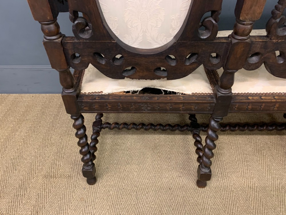 A 19th-century Carolean style carved walnut settee with three oval back panels upholstered in cream damask fabric, featuring barley twist uprights and intricate scrollwork. View XIV