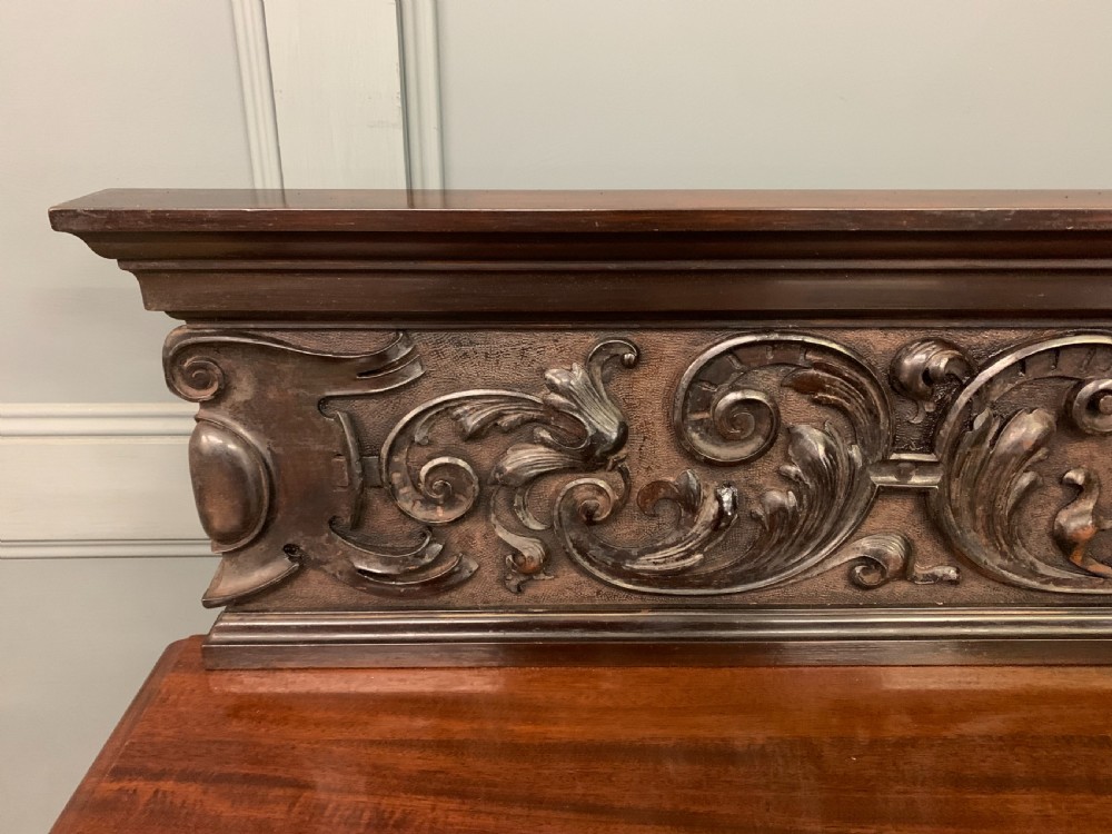 A Victorian dark mahogany buffet featuring a scroll-carved backboard, two drawers with brass handles, fluted front columns, and an open lower tier. View IX