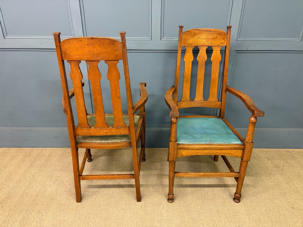 A pair of high-backed Arts and Crafts oak armchairs with vertical back splats and studded leather seats. View V