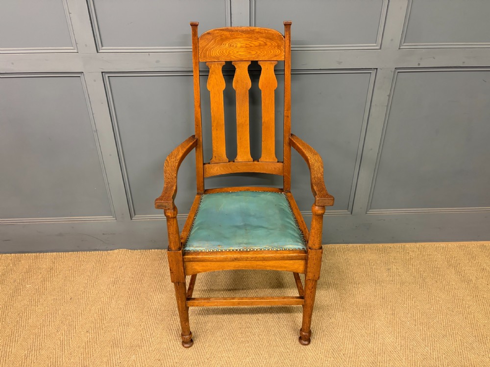 A pair of high-backed Arts and Crafts oak armchairs with vertical back splats and studded leather seats. View VI