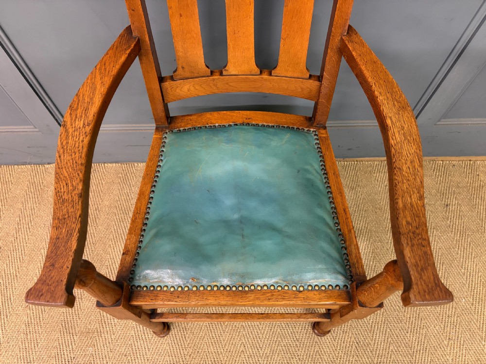 A pair of high-backed Arts and Crafts oak armchairs with vertical back splats and studded leather seats. View VII
