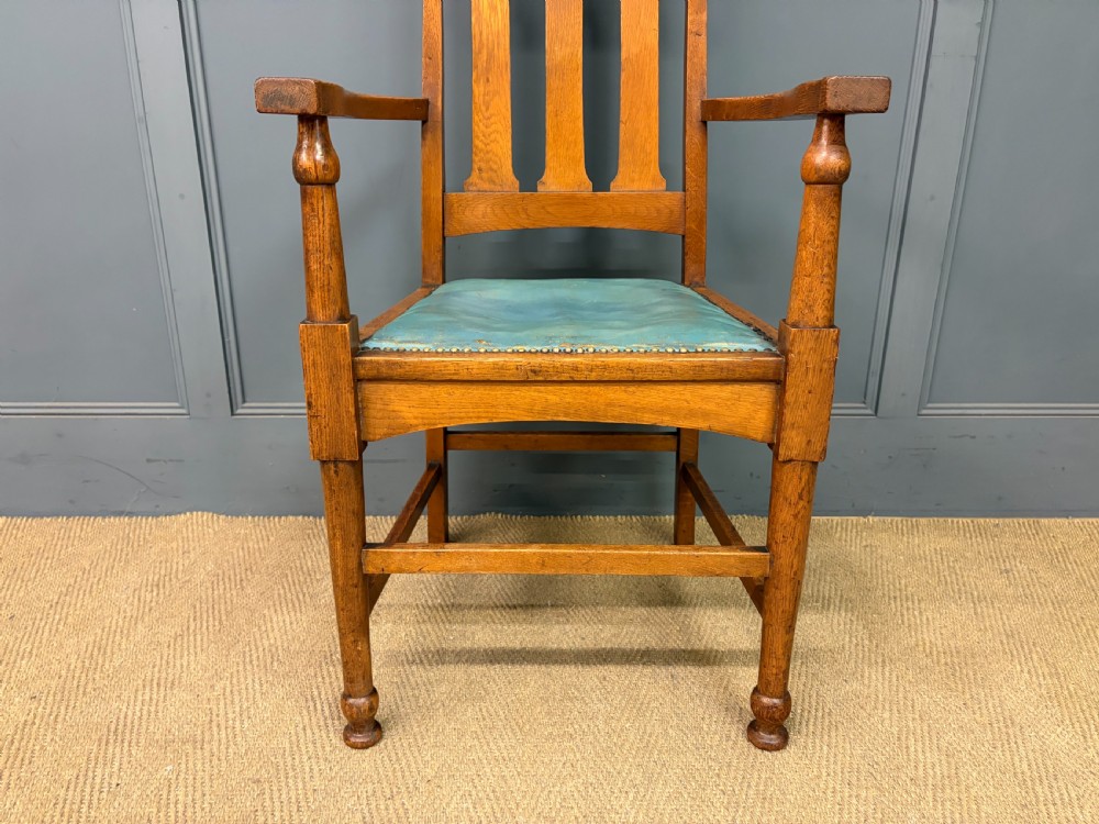 A pair of high-backed Arts and Crafts oak armchairs with vertical back splats and studded leather seats. View IX