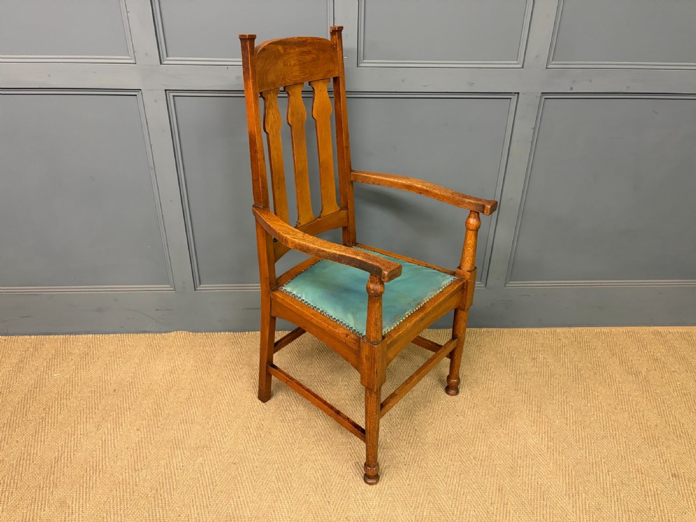 A pair of high-backed Arts and Crafts oak armchairs with vertical back splats and studded leather seats. View X