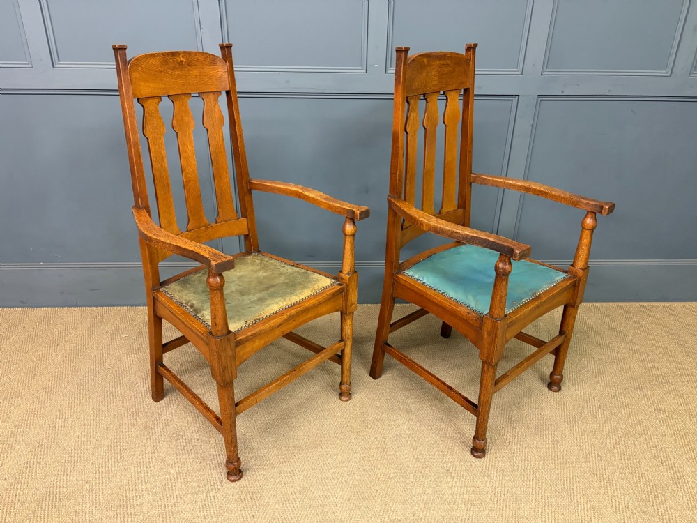 A pair of high-backed Arts and Crafts oak armchairs with vertical back splats and studded leather seats. View XIV