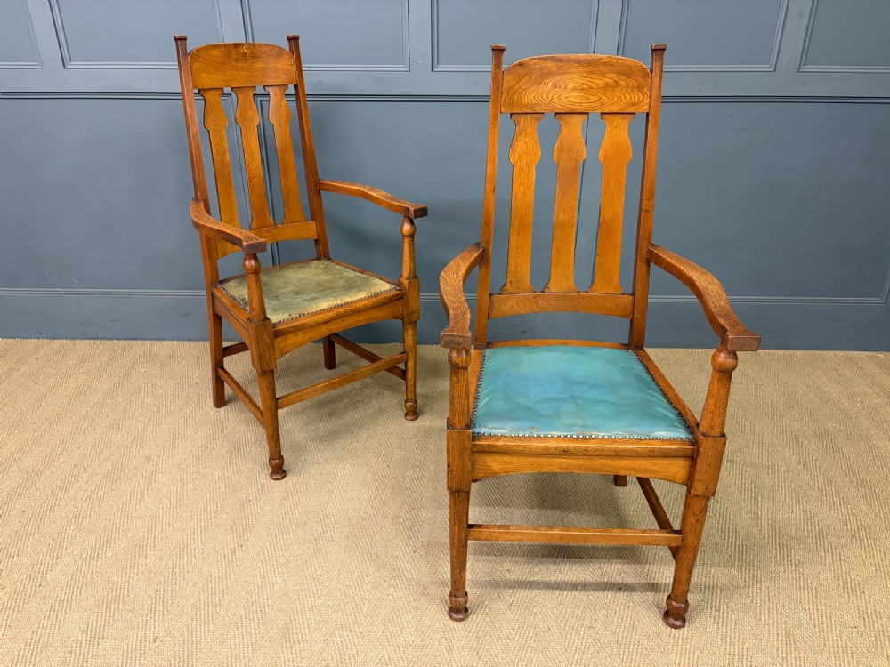 A pair of high-backed Arts and Crafts oak armchairs with vertical back splats and studded leather seats. View XVI