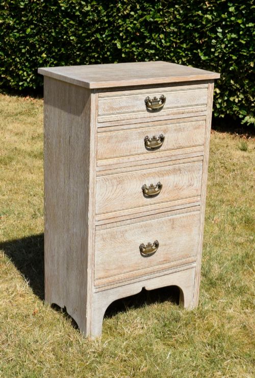 fig 1. A tall Edwardian limed oak chest of drawers with four graduated drawers, brass handles, and a shaped apron base.