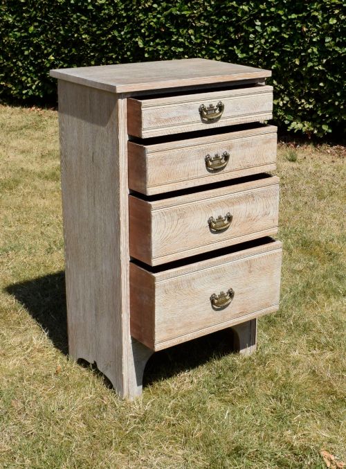 fig 2. A tall Edwardian limed oak chest of drawers with four graduated drawers, brass handles, and a shaped apron base.