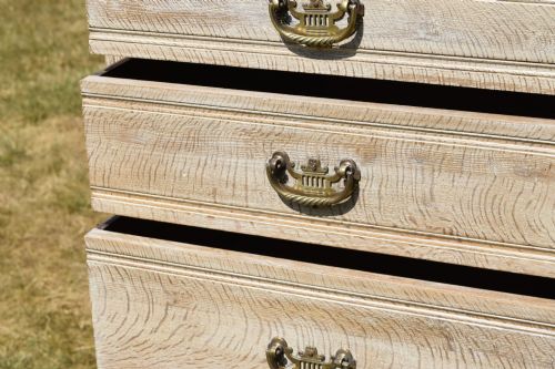 fig 6. A tall Edwardian limed oak chest of drawers with four graduated drawers, brass handles, and a shaped apron base.