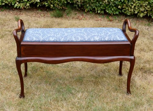 fig 2. A mahogany duet piano stool with a blue patterned upholstered seat and carved cabriole legs.