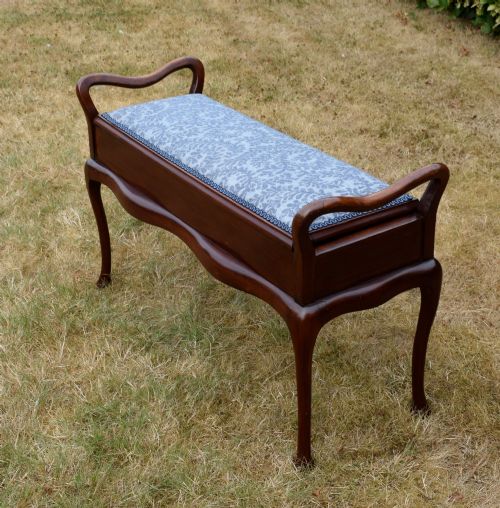 fig 3. A mahogany duet piano stool with a blue patterned upholstered seat and carved cabriole legs.