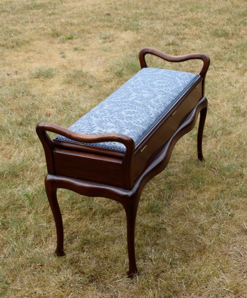 fig 4. A mahogany duet piano stool with a blue patterned upholstered seat and carved cabriole legs.
