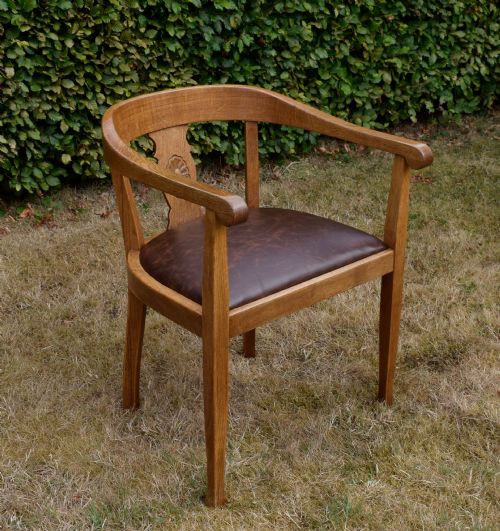 fig 3. An early 20th-century oak desk chair featuring a curved horseshoe backrest, a carved central splat, and a dark brown upholstered seat pad.