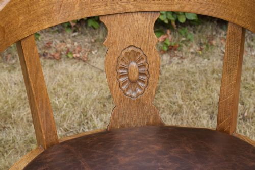 fig 4. An early 20th-century oak desk chair featuring a curved horseshoe backrest, a carved central splat, and a dark brown upholstered seat pad.