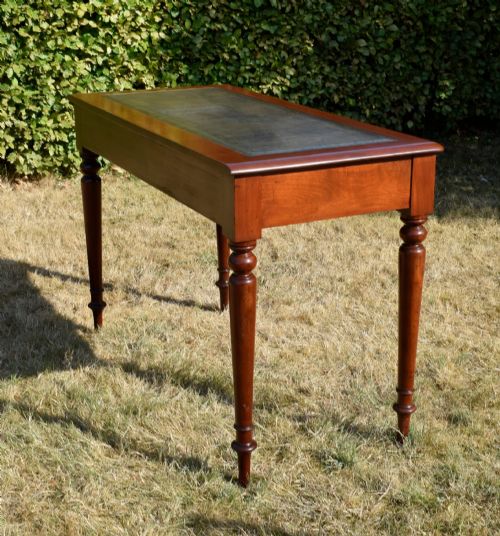 fig 4. A Victorian mahogany writing desk featuring a green leather inset top with gold tooling, two frieze drawers with turned knob handles, and four slender turned legs.