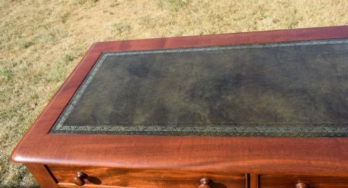 fig 5. A Victorian mahogany writing desk featuring a green leather inset top with gold tooling, two frieze drawers with turned knob handles, and four slender turned legs.