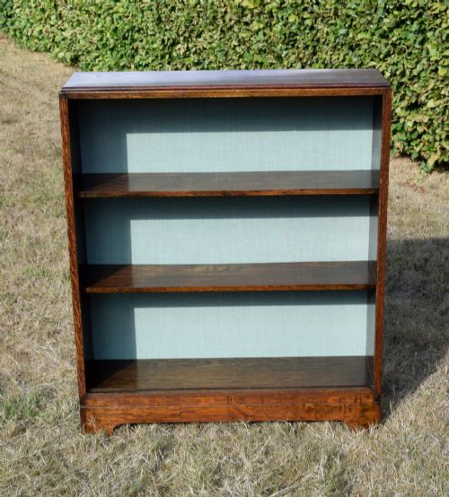 fig 3. A dark oak Art Deco open bookcase featuring three shelves and a light duck-egg blue textured back panel.