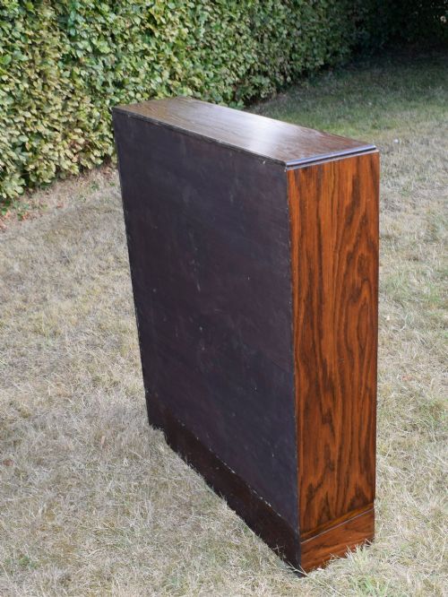 fig 4. A dark oak Art Deco open bookcase featuring three shelves and a light duck-egg blue textured back panel.