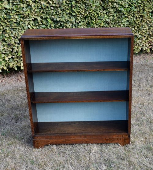 fig 6. A dark oak Art Deco open bookcase featuring three shelves and a light duck-egg blue textured back panel.