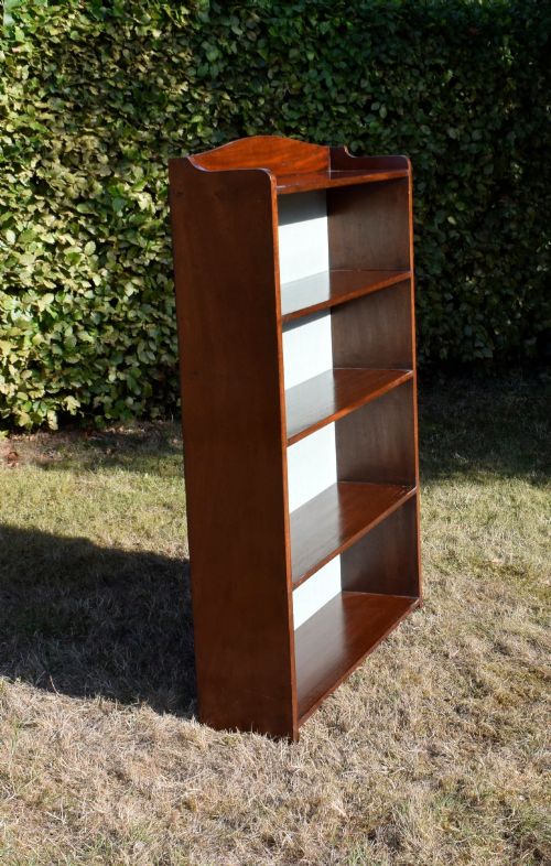 fig 4. A standing mahogany open bookcase featuring four horizontal shelves, a gently curved top upstand, and a light-coloured fabric back panel.