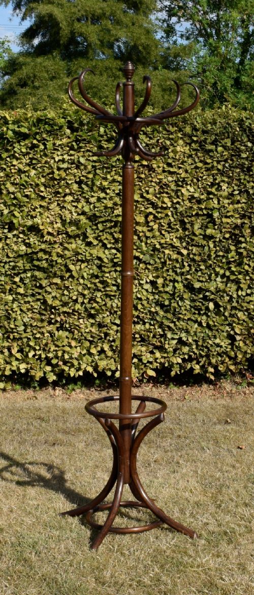 fig 3. A dark brown bentwood coat and hat stand featuring curved upper hooks, a turned central post, an umbrella ring, and curved tripod legs.