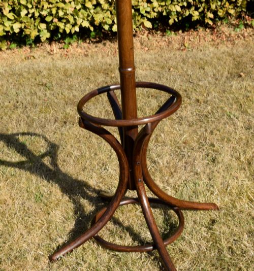 fig 6. A dark brown bentwood coat and hat stand featuring curved upper hooks, a turned central post, an umbrella ring, and curved tripod legs.