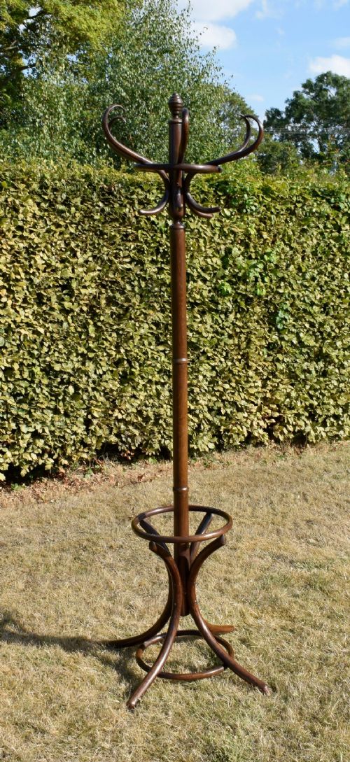 fig 7. A dark brown bentwood coat and hat stand featuring curved upper hooks, a turned central post, an umbrella ring, and curved tripod legs.