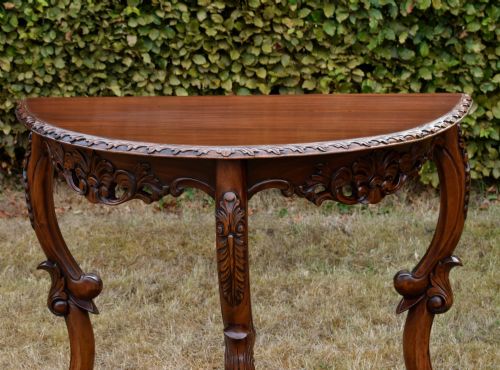 fig 1. A dark mahogany demi-lune console table featuring deep acanthus leaf carvings on the frieze and three cabriole legs.