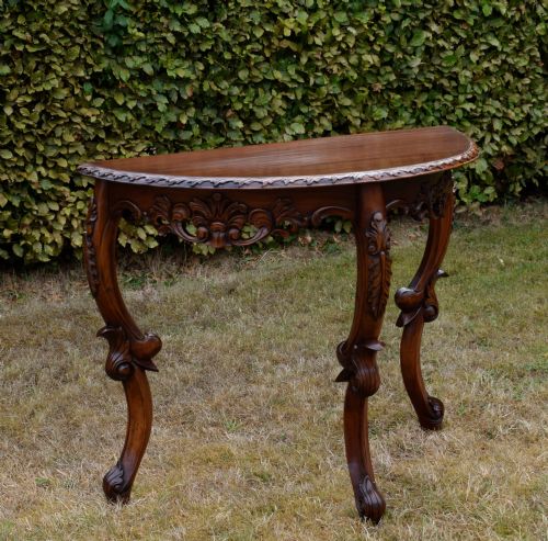 fig 2. A dark mahogany demi-lune console table featuring deep acanthus leaf carvings on the frieze and three cabriole legs.