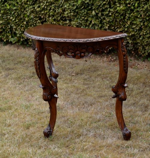 fig 4. A dark mahogany demi-lune console table featuring deep acanthus leaf carvings on the frieze and three cabriole legs.